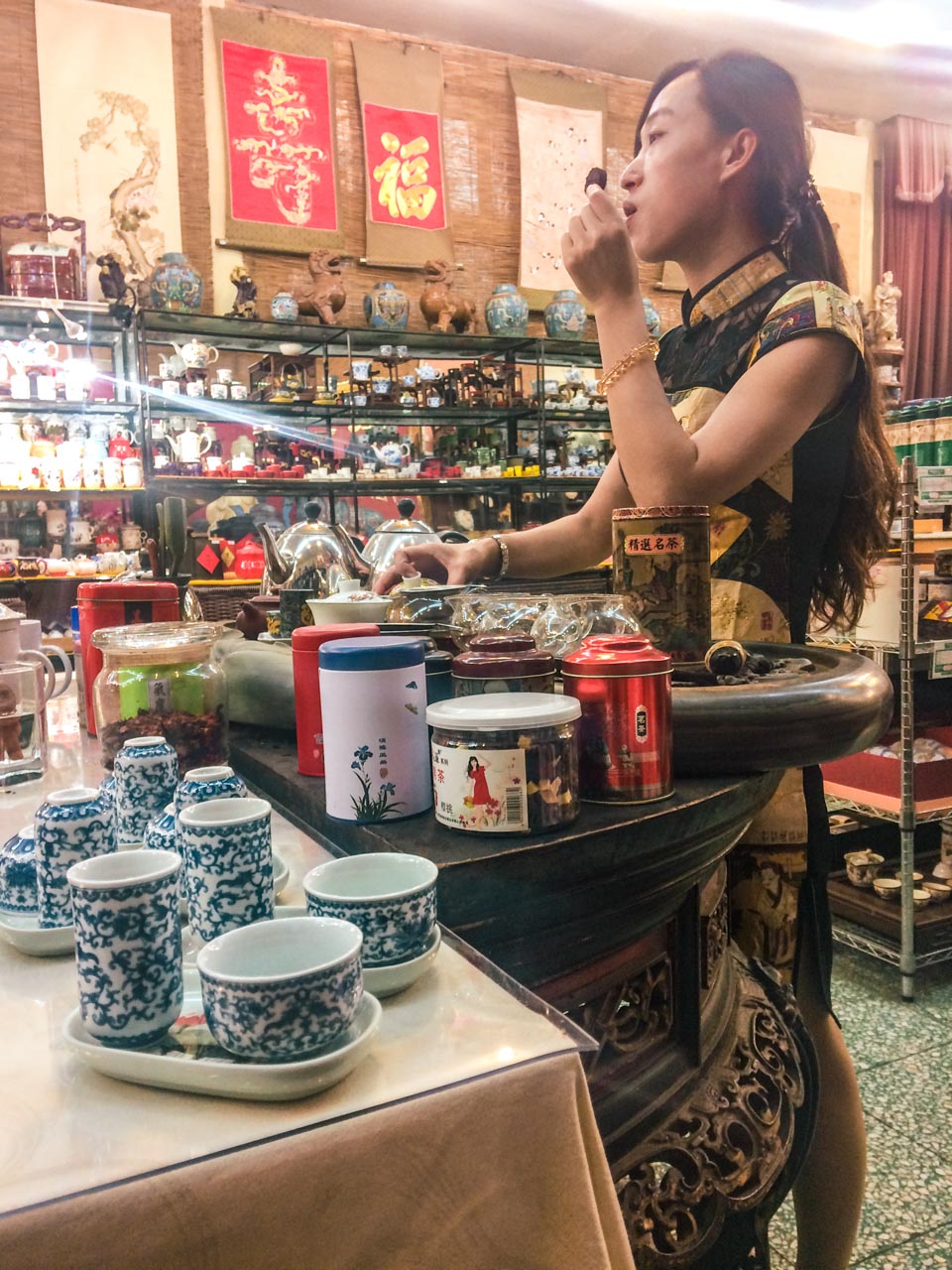 A Chinese woman holding up tea during the tea tasting ceremony at a traditional tea shop in Beijing