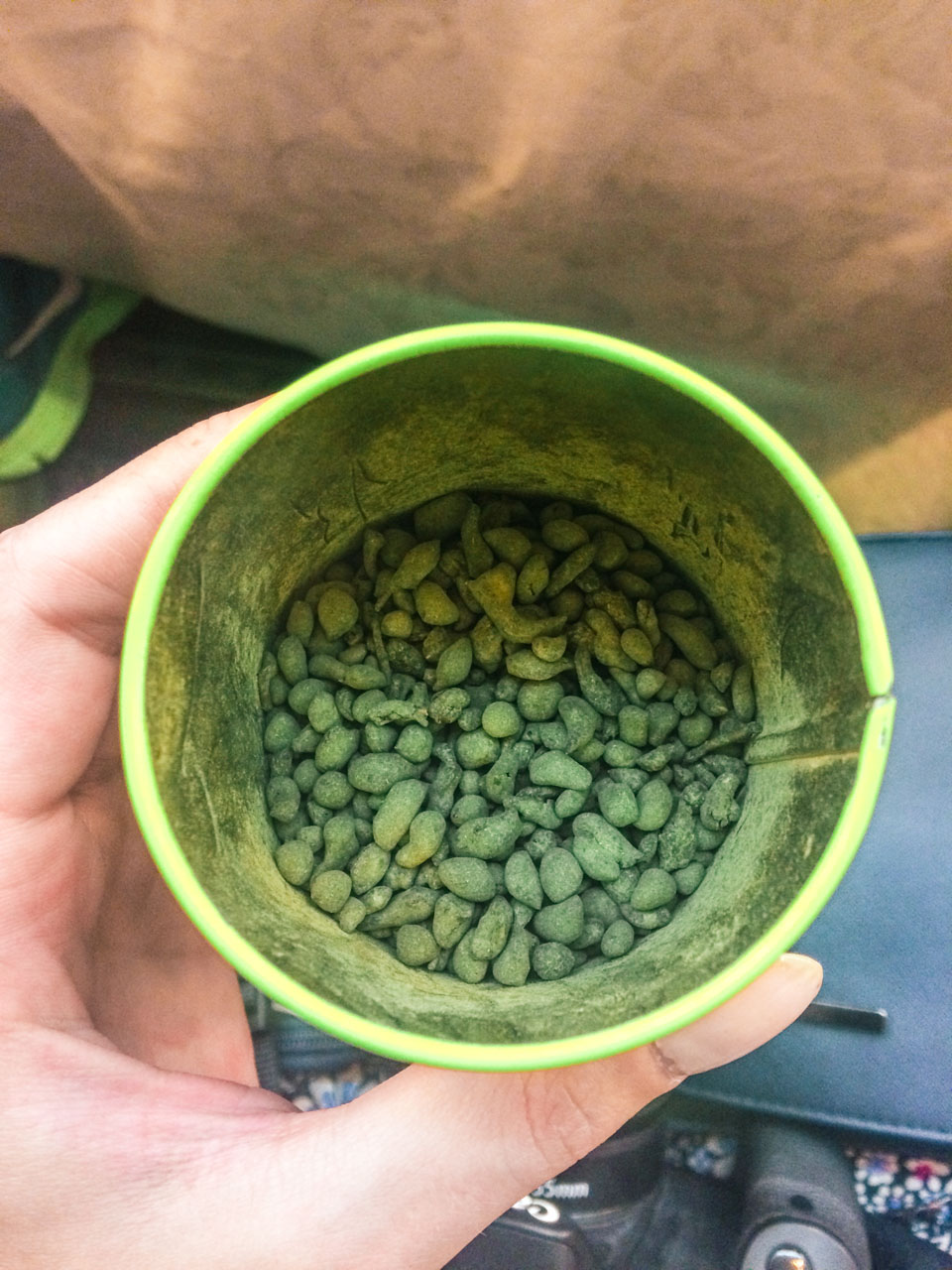 Woman's hand holding a tea tin containing jasmine tea pearls at a traditional tea shop