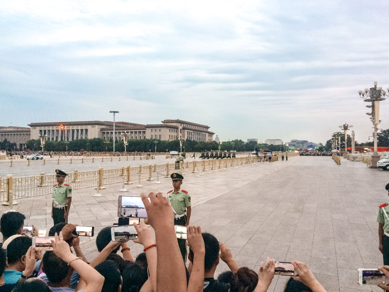 Crowds of tourists taking photos of security guards marching towards the Tiananmen Gate in Beijing