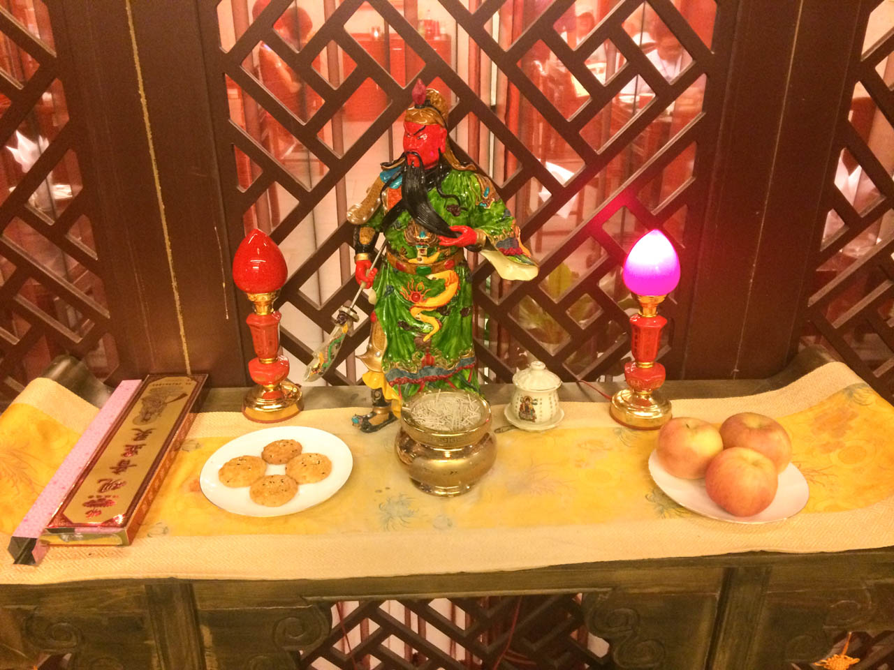 A little Chinese altar with various offerings, including apples and biscuits