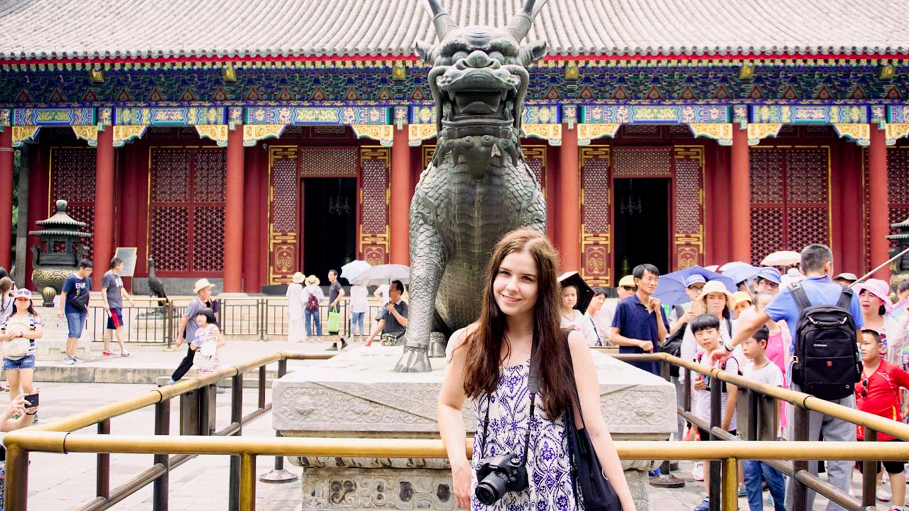 Smiling girl standing in front of a mythical dragon sculpture at the Summer Palace in Beijing, China