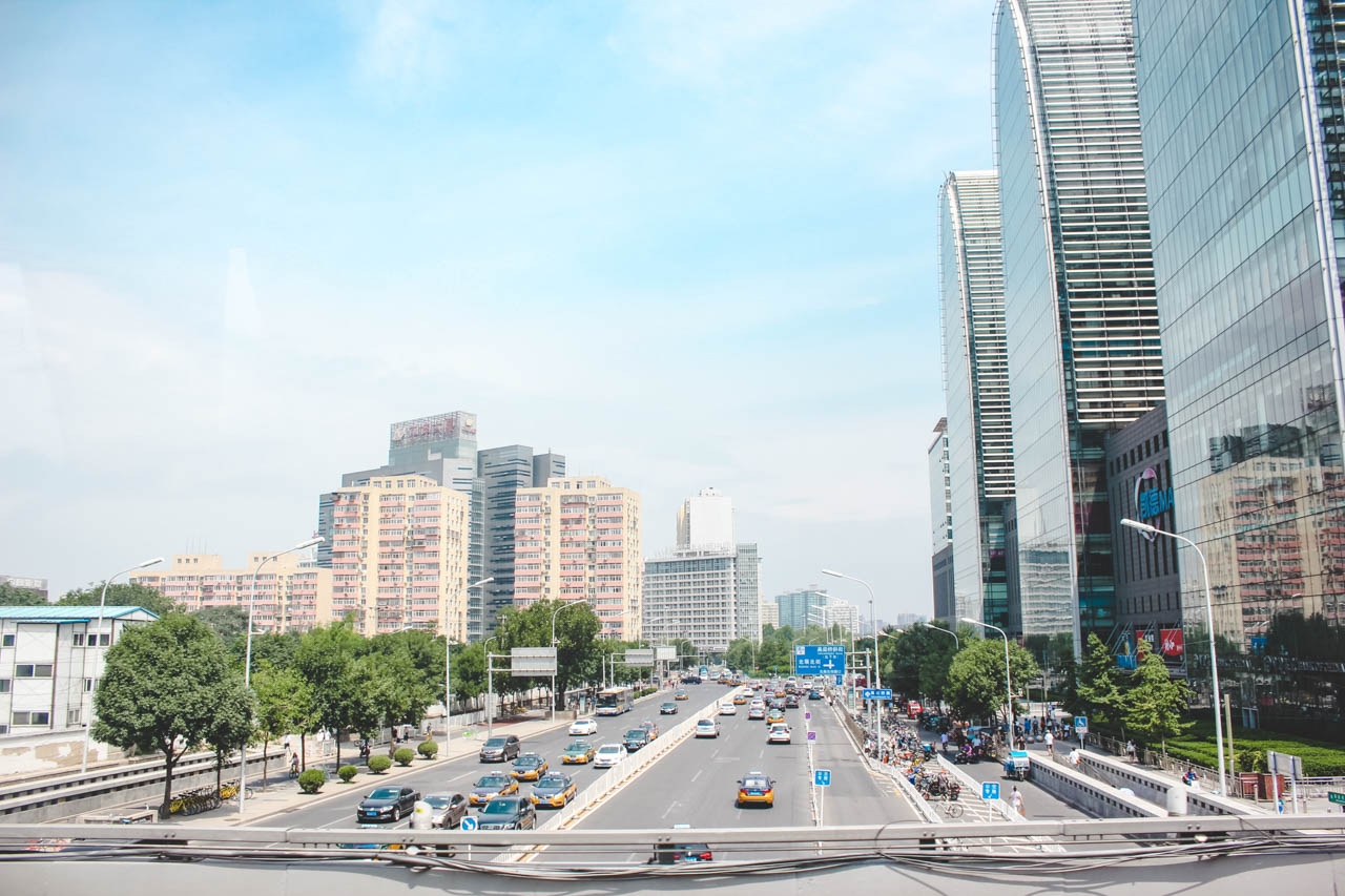 Cars driving down a road in Beijing, with the Capital Mall Wangjing visible on the far right side