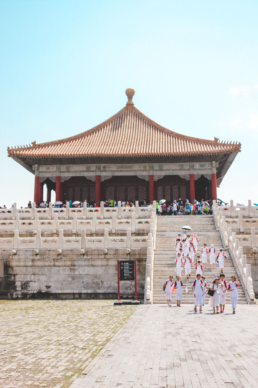 Group of Chinese students dressed in white walking down the stairs at the Forbidden City in Beijing