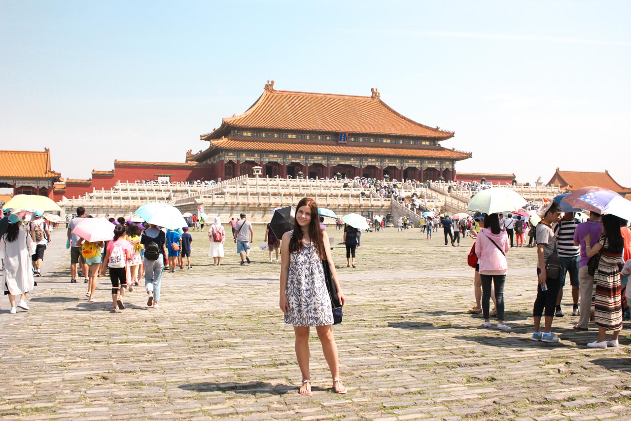 Girl in a white and blue summer dress standing on a square inside the Forbidden City in Beijing