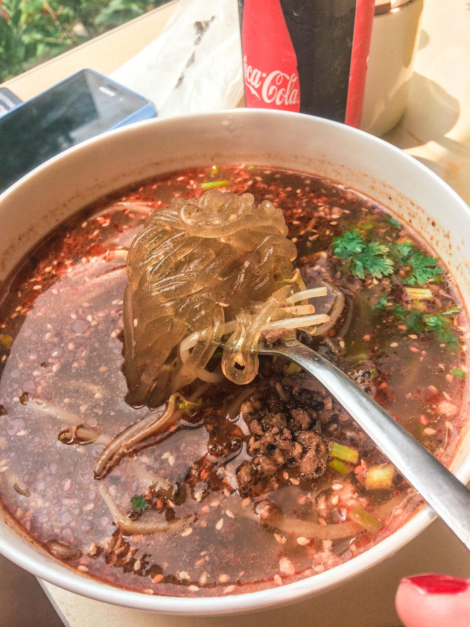 A close-up shot of rice noodles on a spoon over a bowl of soup at a restaurant in Beijing, China