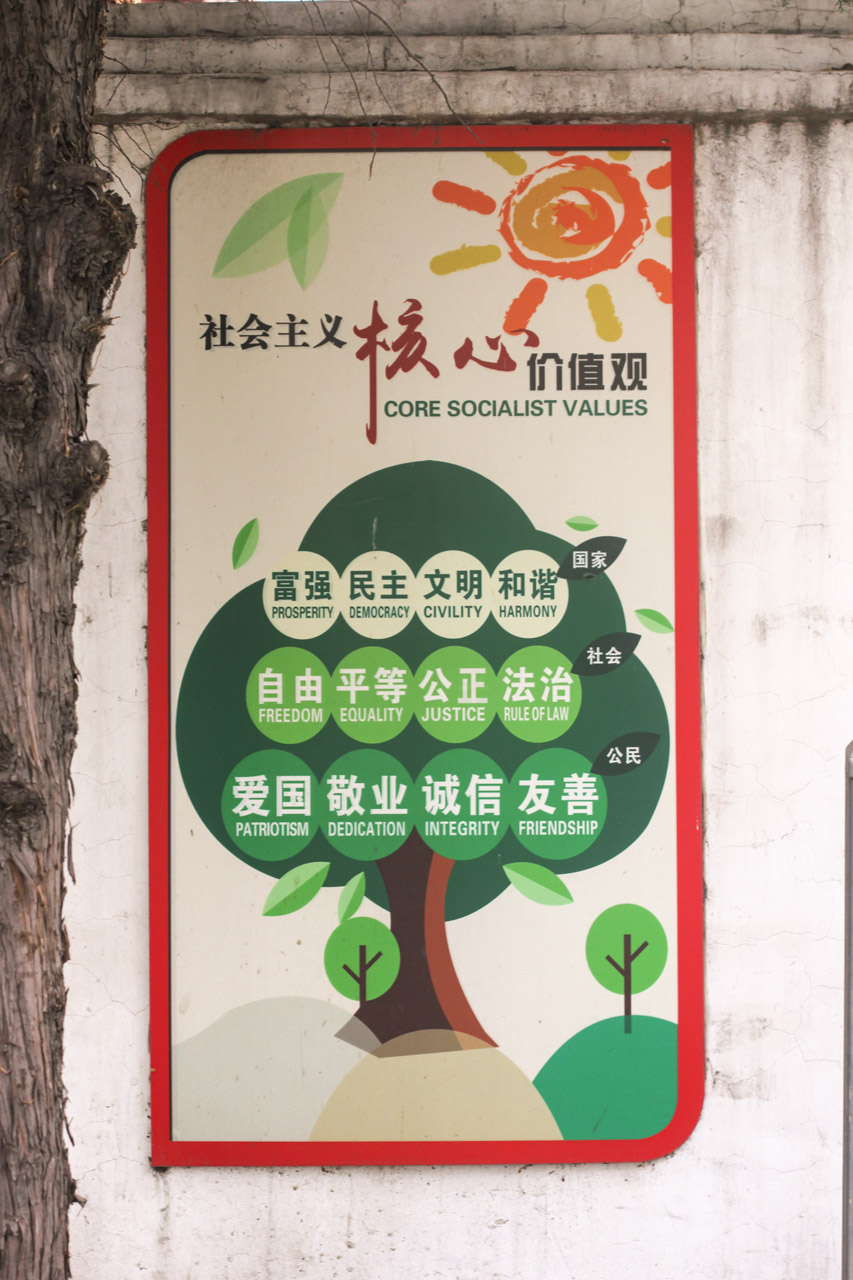 Metal wall sign depicting a tree with "Core socialist values" written on it in a street in Beijing