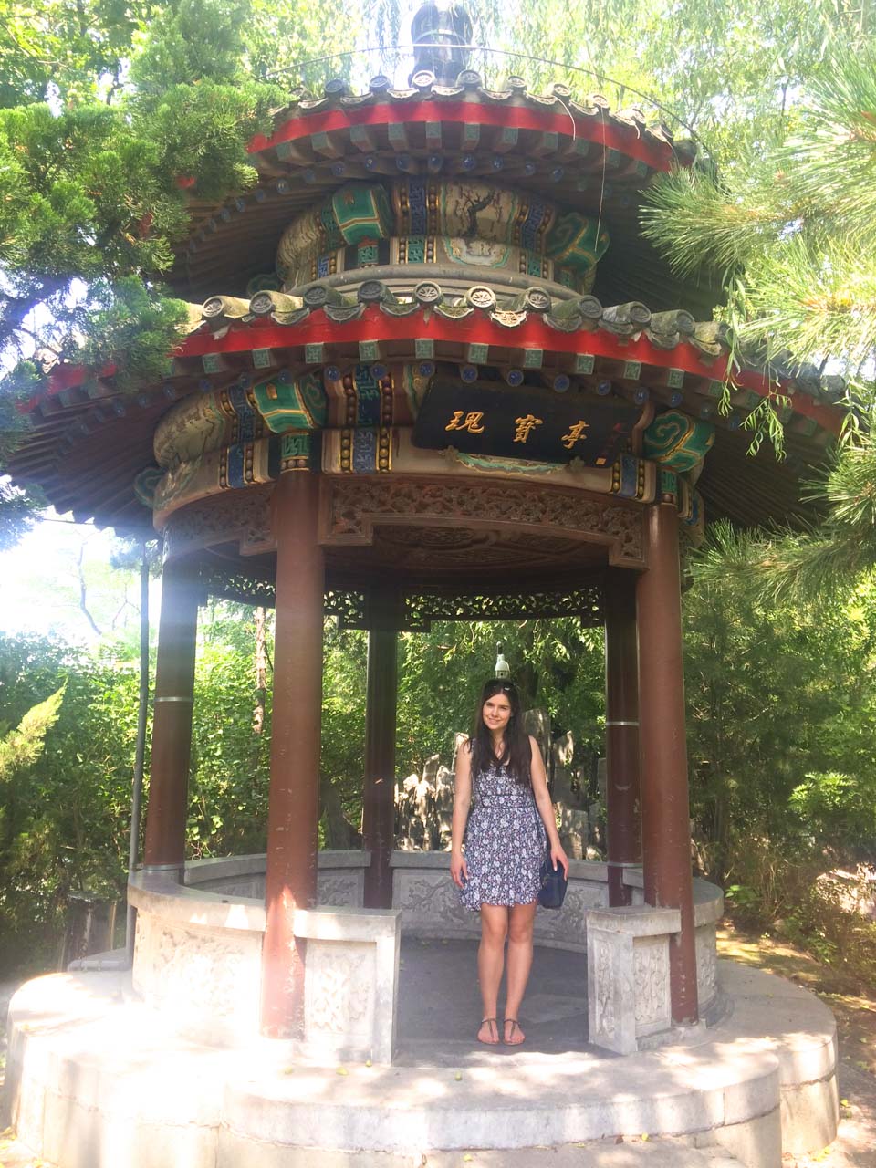 Woman in a short floral dress standing in front of a traditional Chinese pavilion in Beijing, China