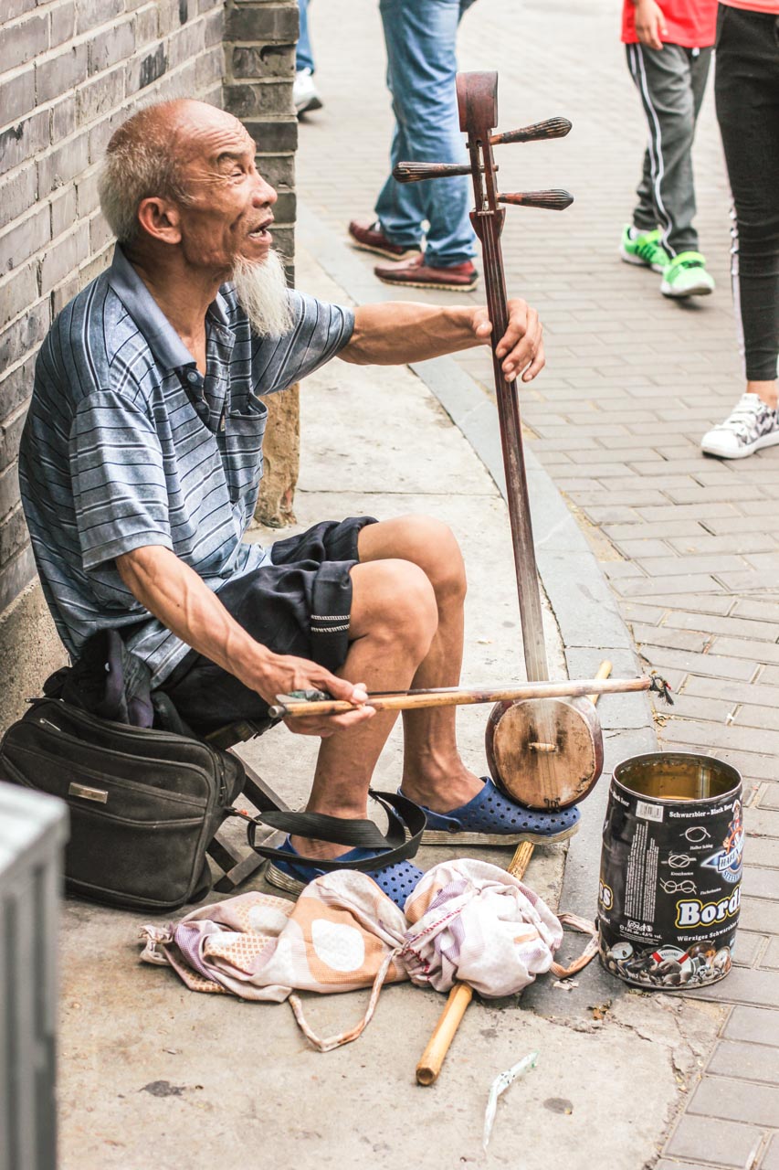 Old Chinese man playing the Banhu, a traditional Chinese string instrument, in a street in Beijing