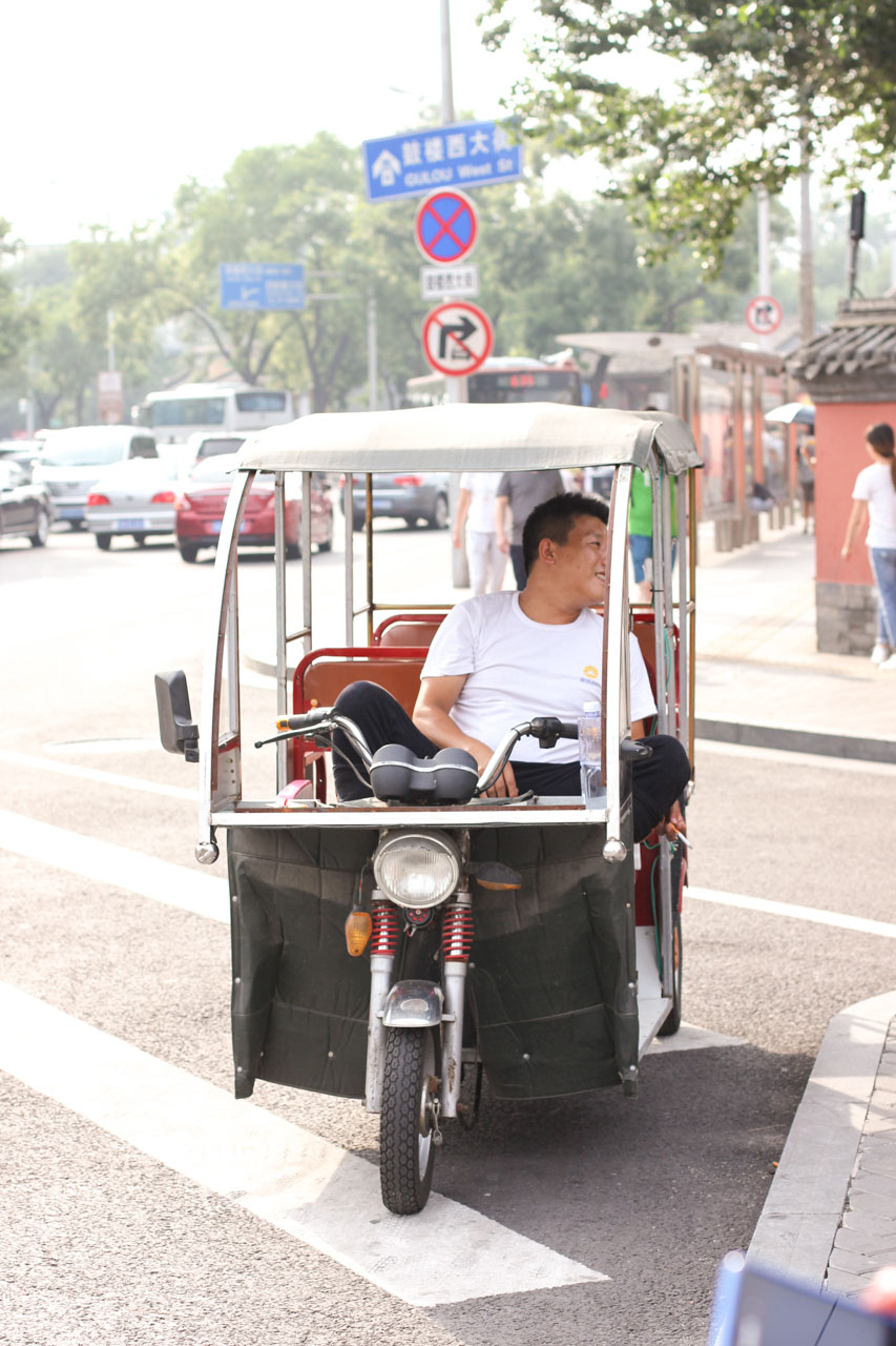 A Chinese rickshaw driver waiting for tourists outside the Bell and Drum Towers in Beijing, China