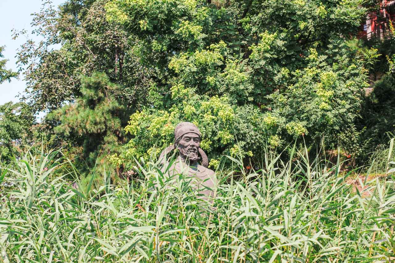 Stone sculpture of Guo Shoujing surrounded by bushes at Huohai Park in Beijing, China