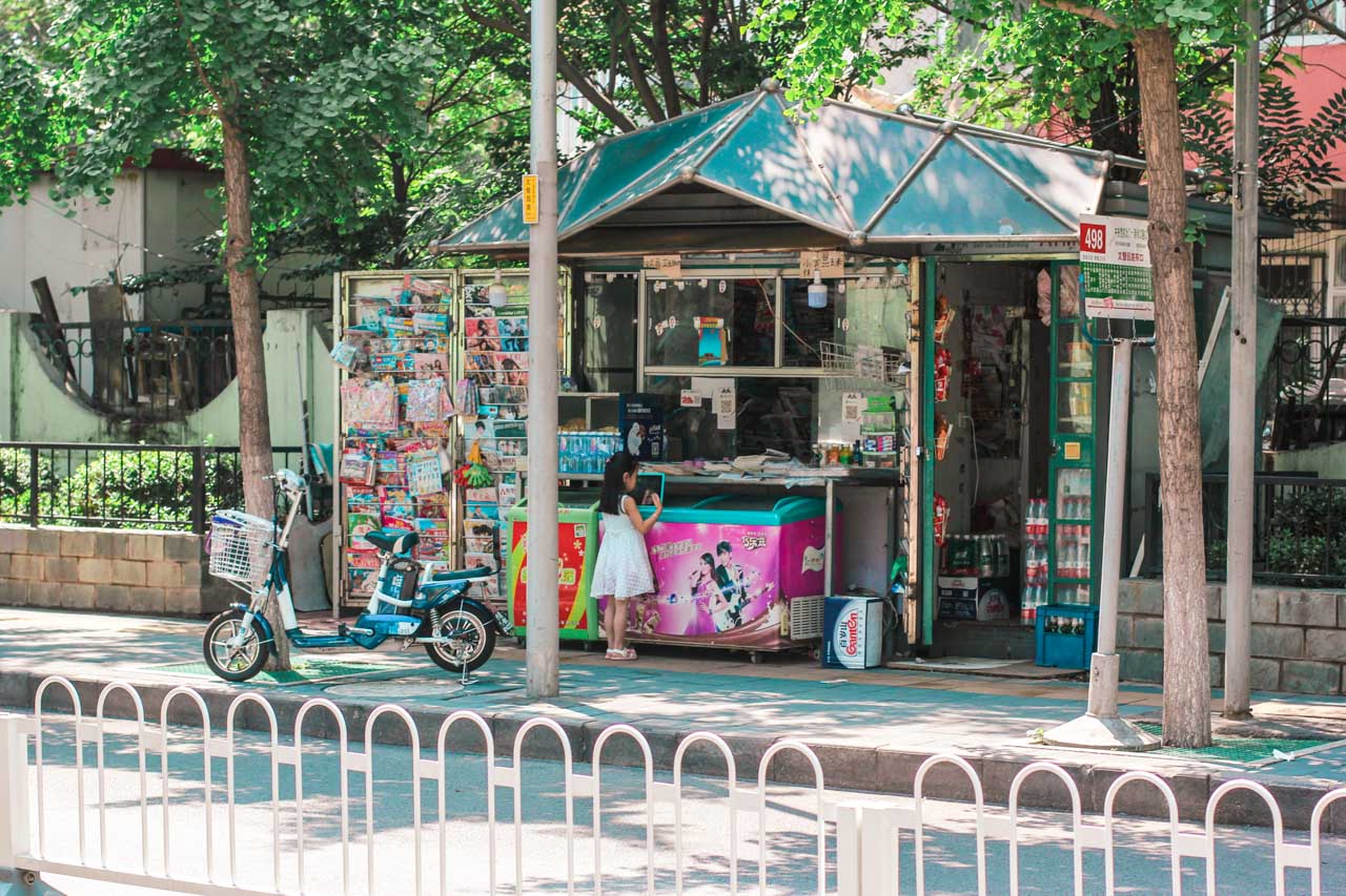 A small Chinese girl buying ice cream from a street kiosk in Beijing, China