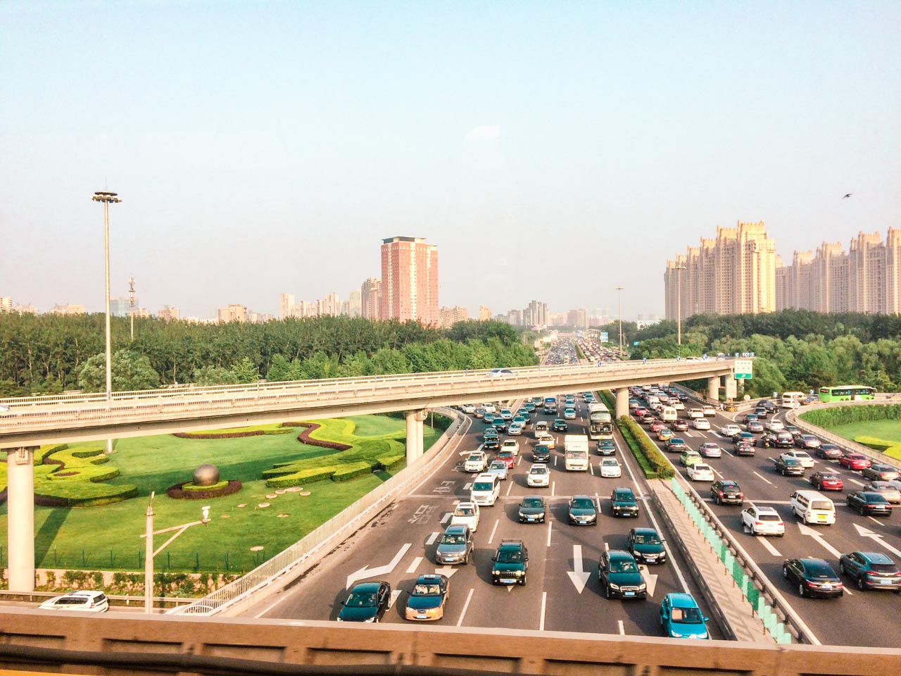 Dozens of cars driving down a busy multi-lane road in Beijing, China
