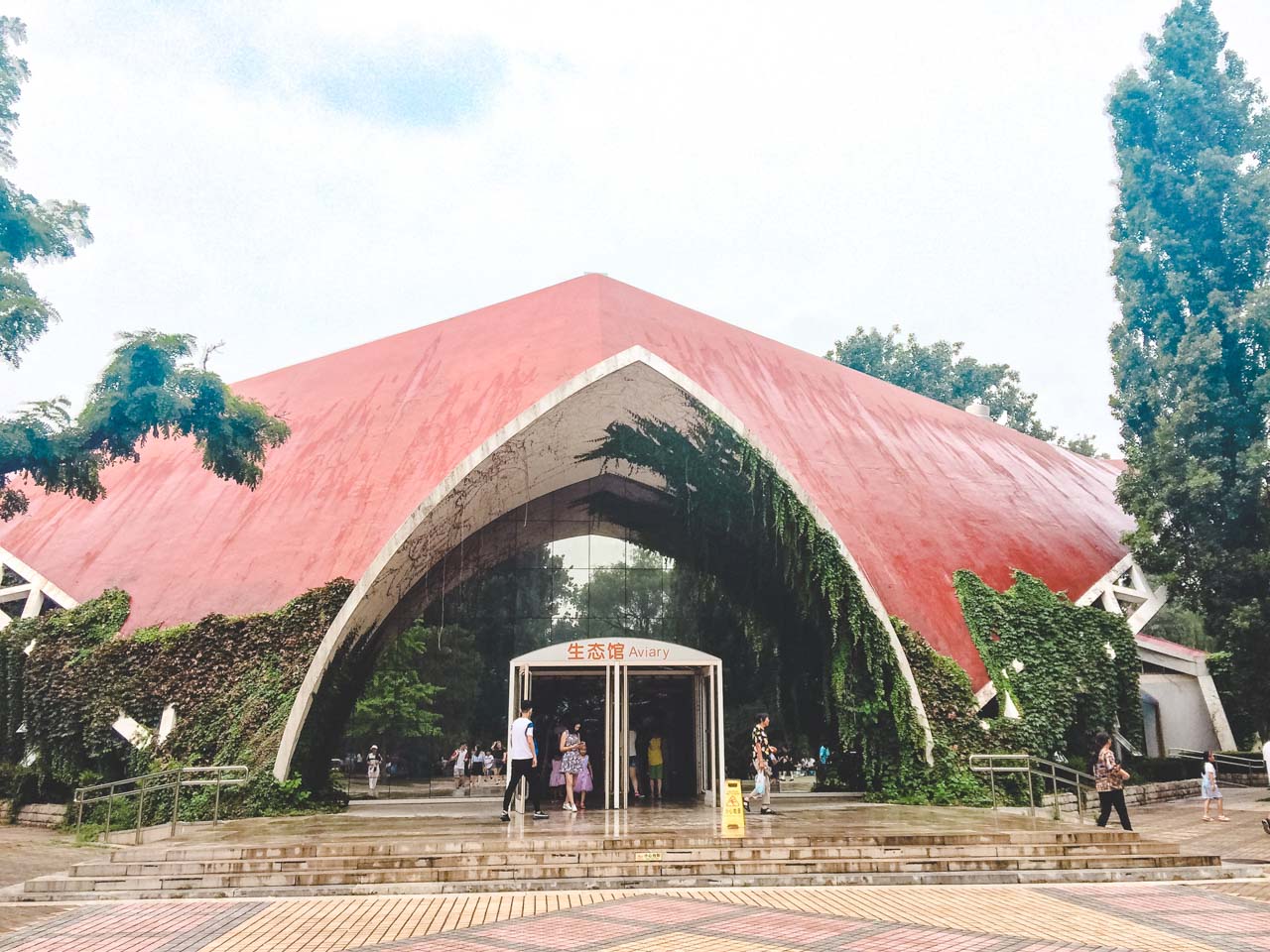 A building partly covered with ivy that houses the bird pavilion at the Beijing Zoo