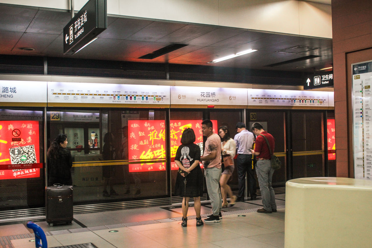 People standing behind glass screen doors, waiting for the subway to arrive in Beijing, China