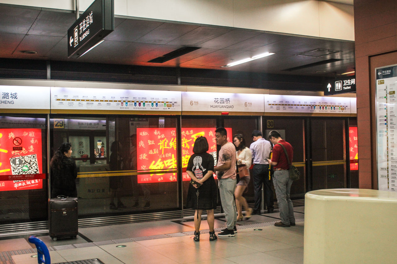 People standing behind glass screen doors, waiting for the subway to arrive in Beijing, China
