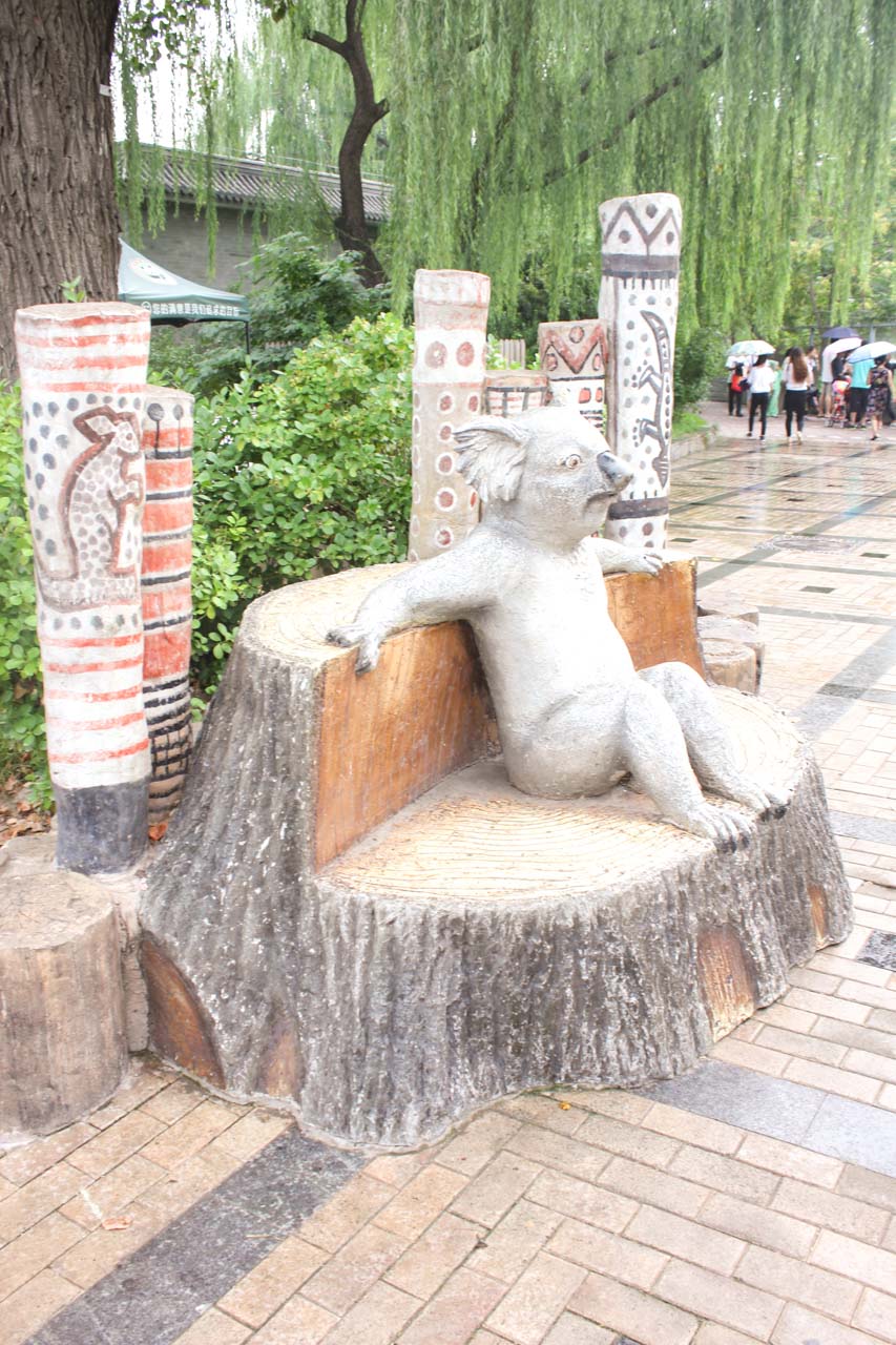 A statue of a koala sitting on a wooden bench at the Beijing Zoo