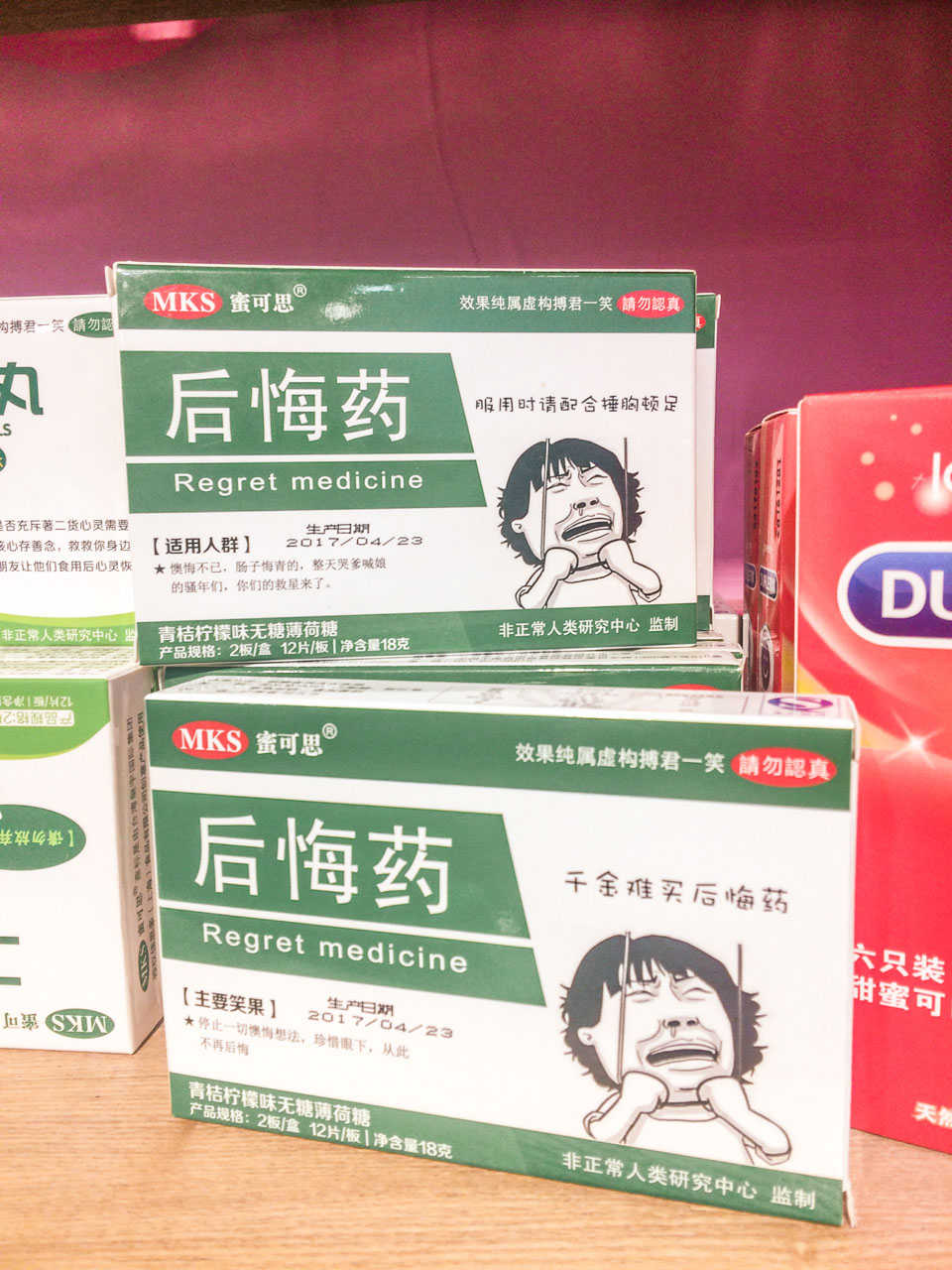 Shelves stacked with "regret medicine" with a crying Asian man on the packaging at a shop in Beijing