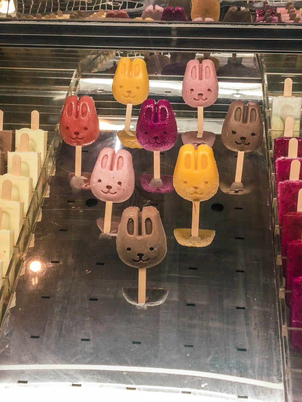 Different types of colourful bunny-shaped ice cream in a glass display case at a shop in Beijing
