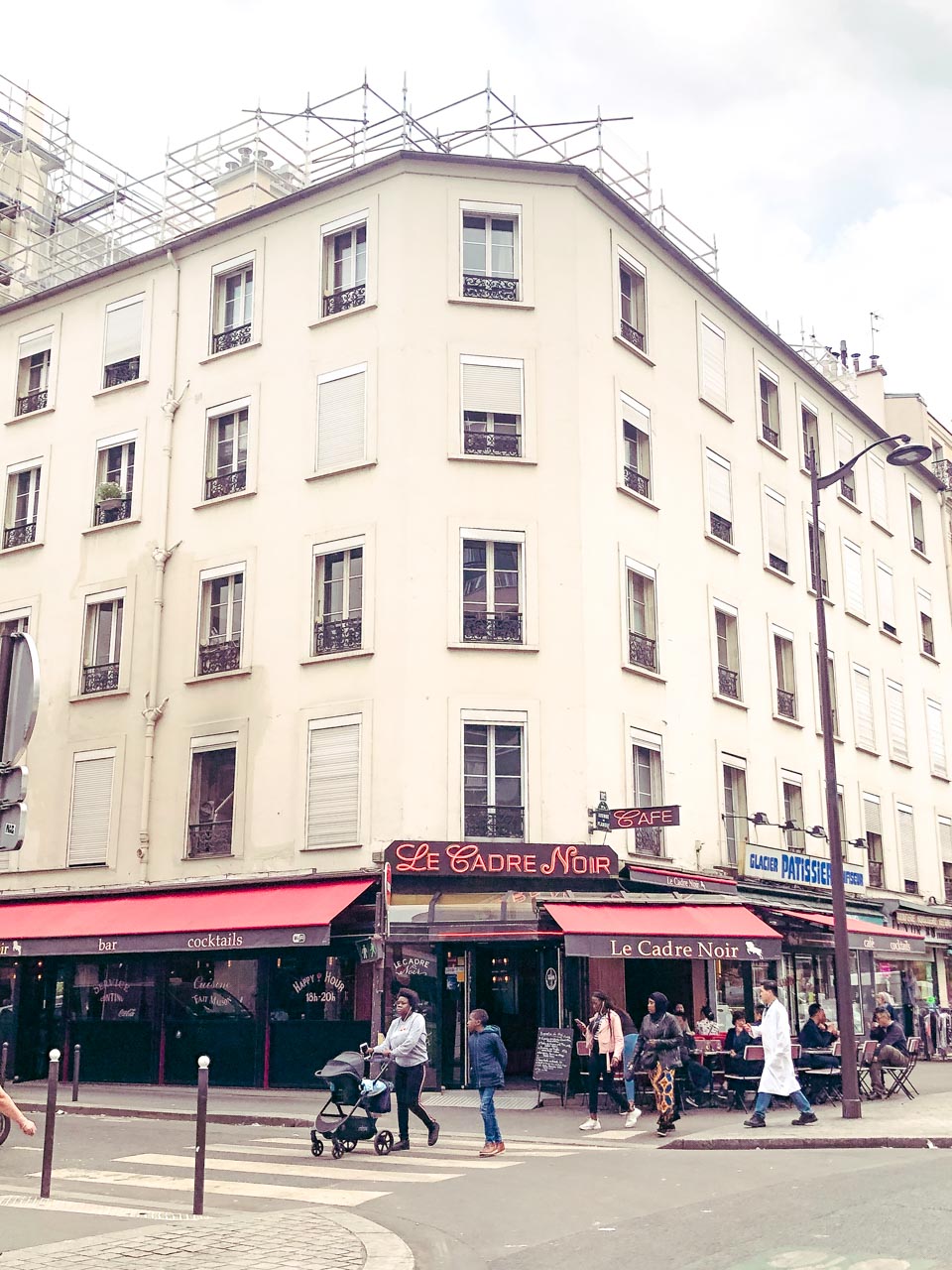 People crossing the street outside the Le Cadre Noir restaurant in Paris, France