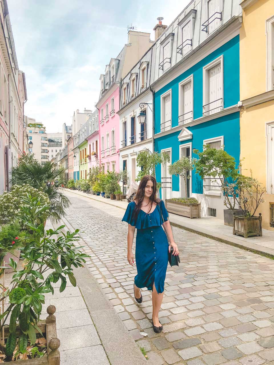 Woman in a blue off-the-shoulder midi dress walking on Rue Crémieux in Paris, France
