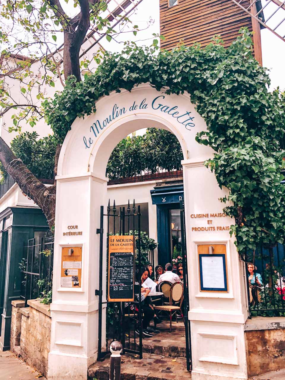 The ivy-covered entrance arch to the famous Le Moulin de la Galette restaurant in Montmartre, Paris