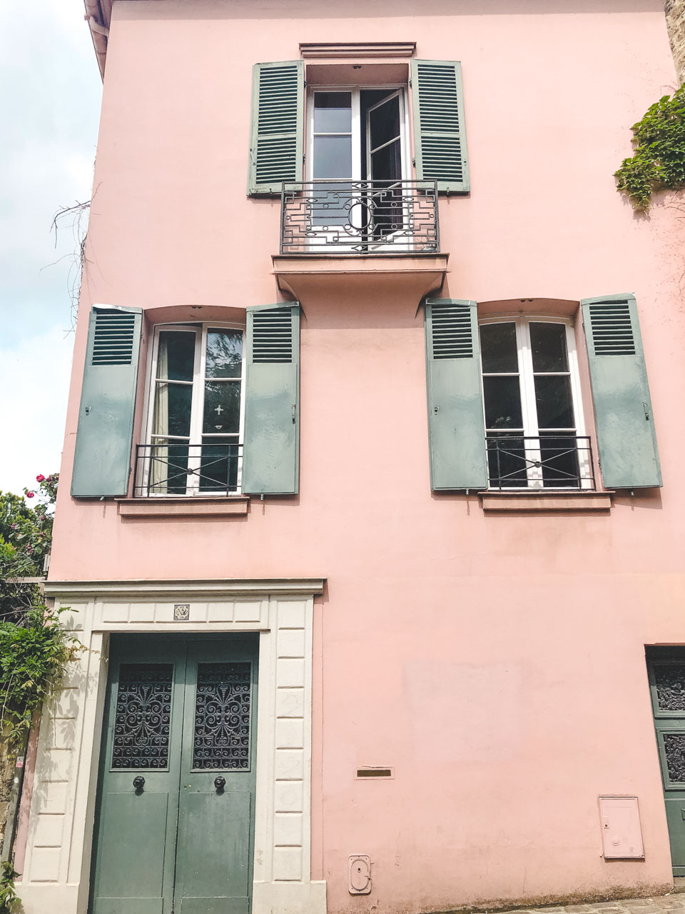A pastel pink house with green window shutters near the Sacré-Cœur basilica in Paris, France