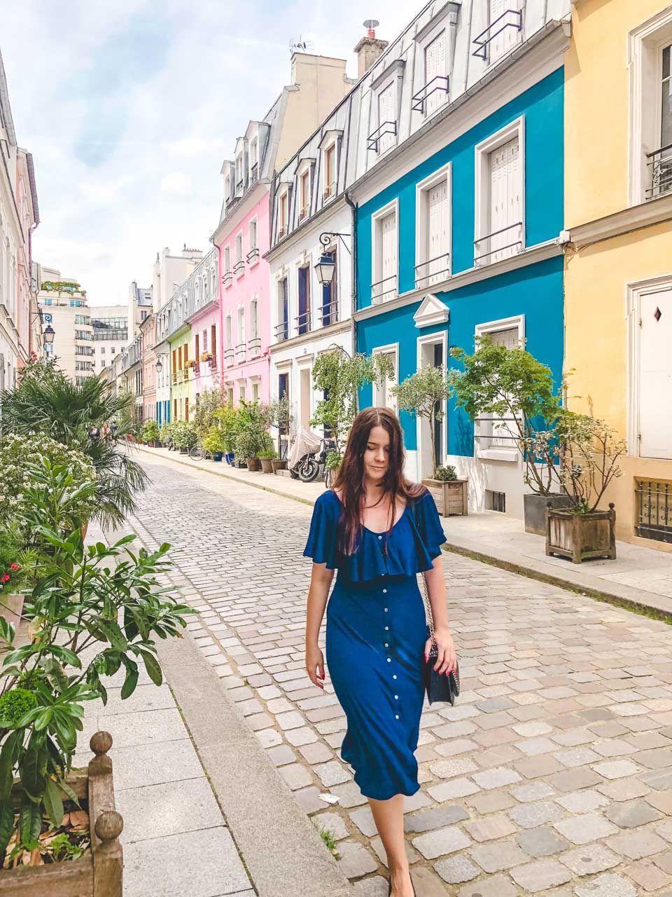 Woman in a blue off-the-shoulder midi dress walking on Rue Crémieux in Paris, France