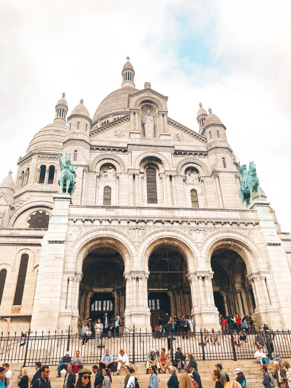 Crowds of tourists on the stairs leading to the Sacré-Cœur basilica in Paris, France