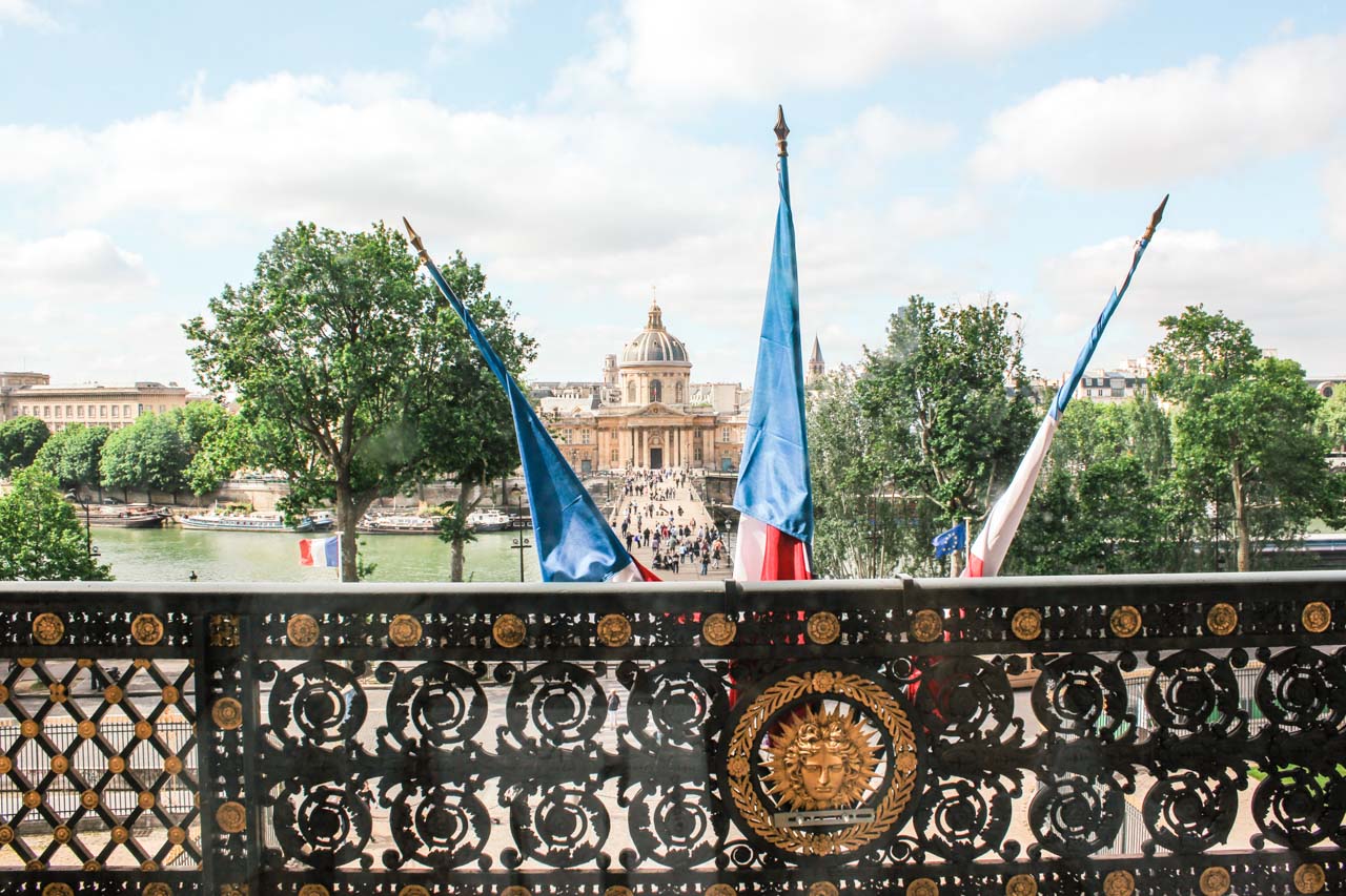 Three French flags hanging on a balcony in the Louvre Museum in Paris, France