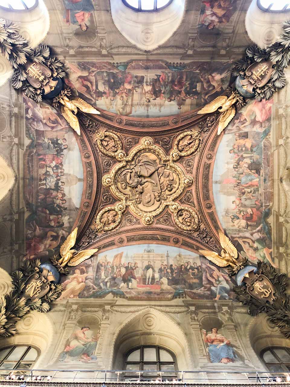 Frescoes on an ornately decorated ceiling in the Louvre Museum in Paris, France