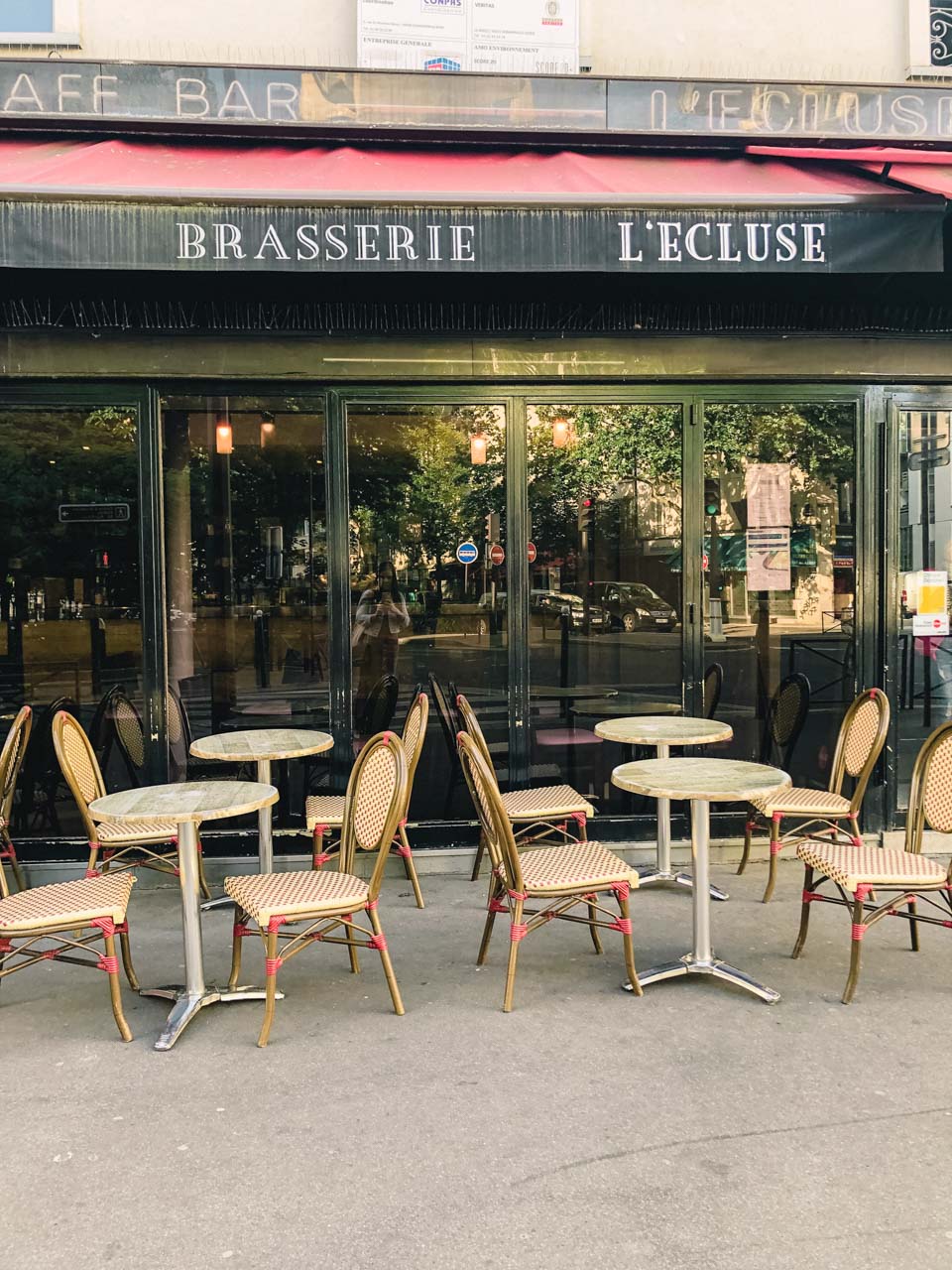 Rows of tables and chairs outside a traditional French brasserie called L'Ecluse in Paris, France
