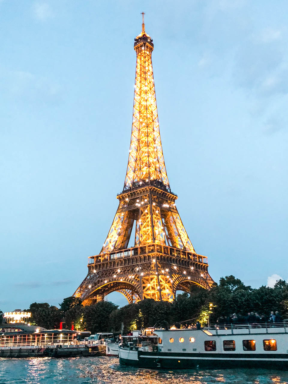 Eiffel Tower twinkling after dark seen from a cruise boat, while another cruise boat is passing by
