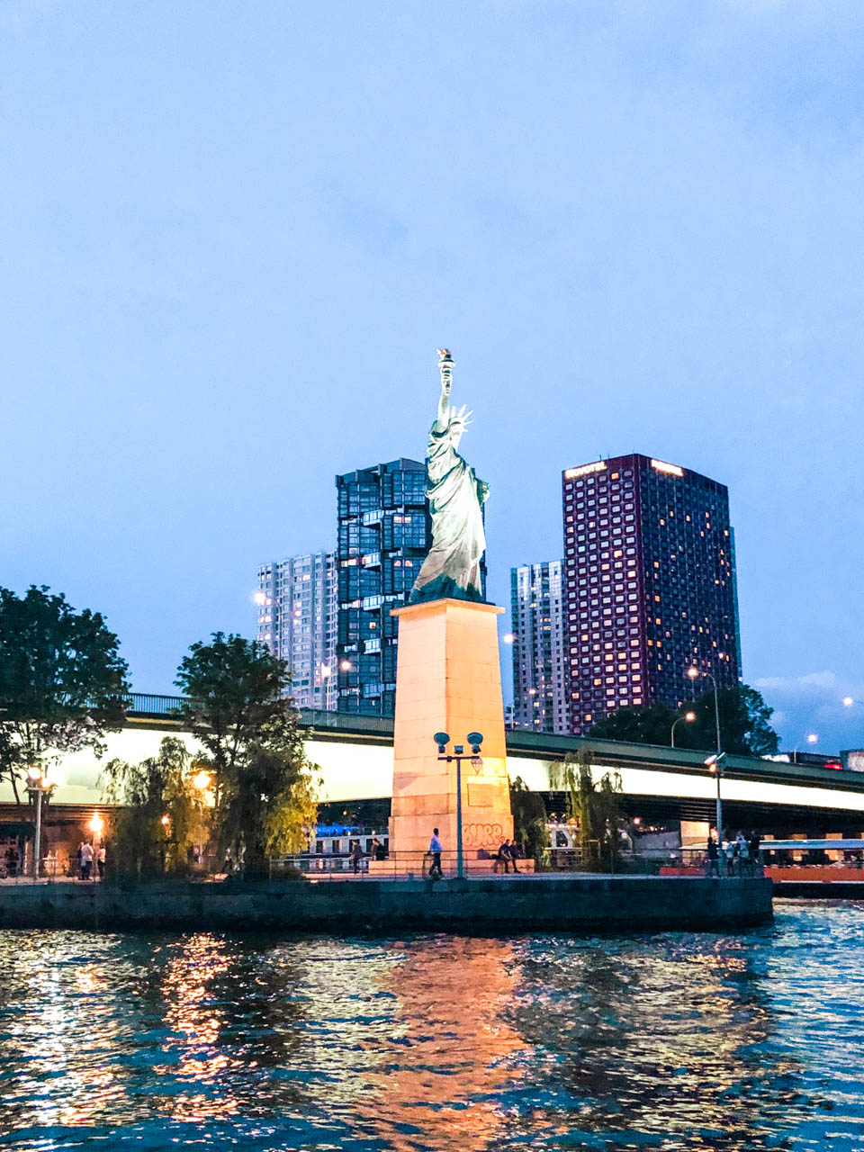 The Pont de Grenelle Statue of Liberty in Paris, France, with various skyscrapers in the background