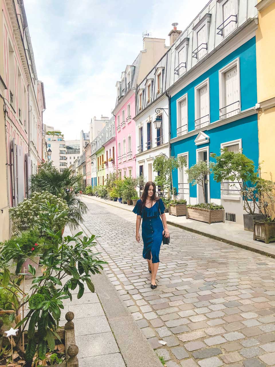 Woman in a blue off-the-shoulder midi dress walking on Rue Crémieux in Paris, France