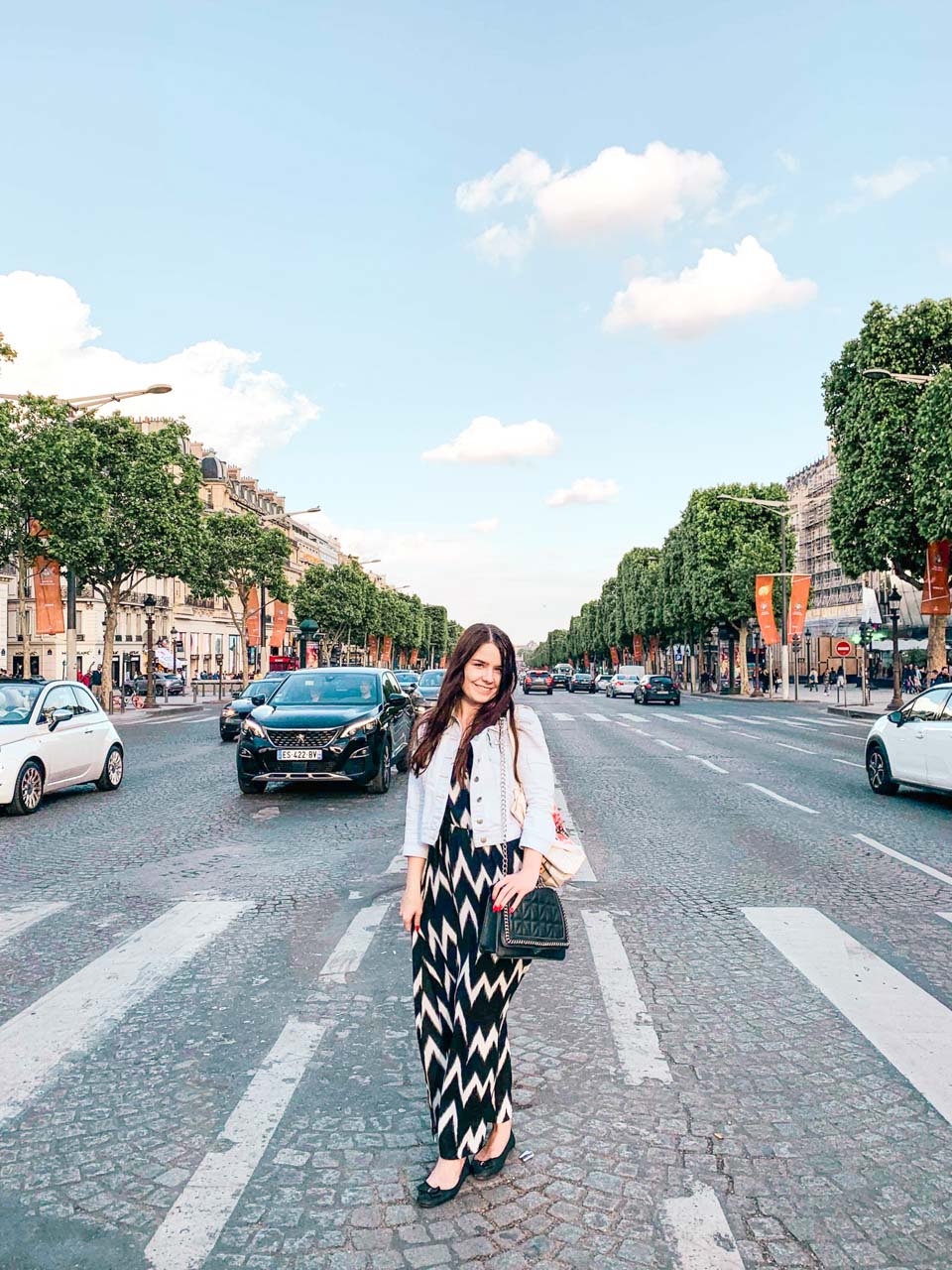 Woman in a black and white maxi dress standing on a street crossing on the Champs-Élysées in Paris