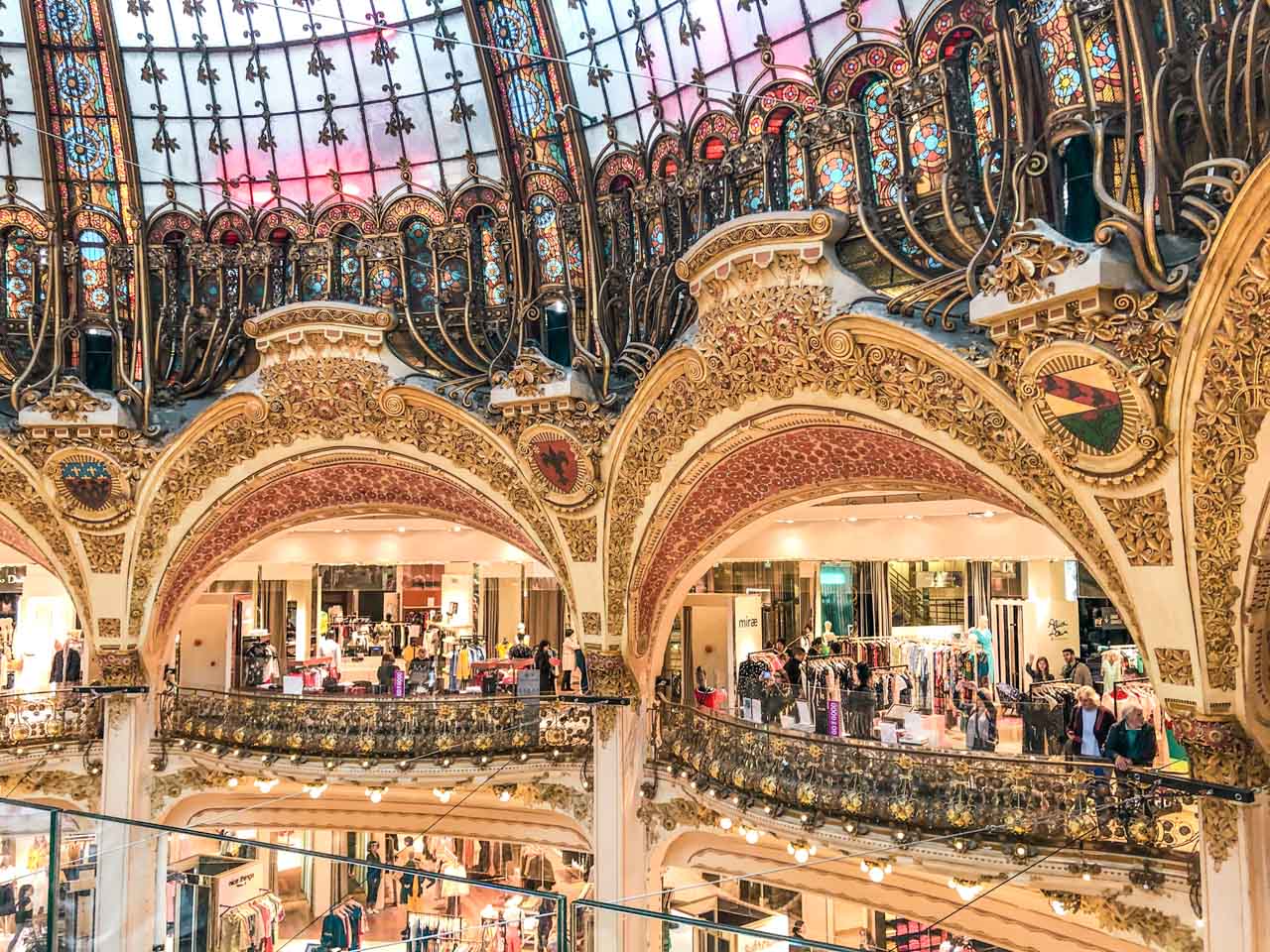 Shops inside loggias formed by ornately decorated golden arches at Galeries Lafayette Paris Hausmann