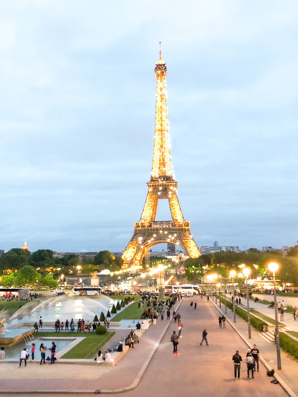People walking in the Jardins du Trocadéro with the Eiffel Tower twinkling in the background