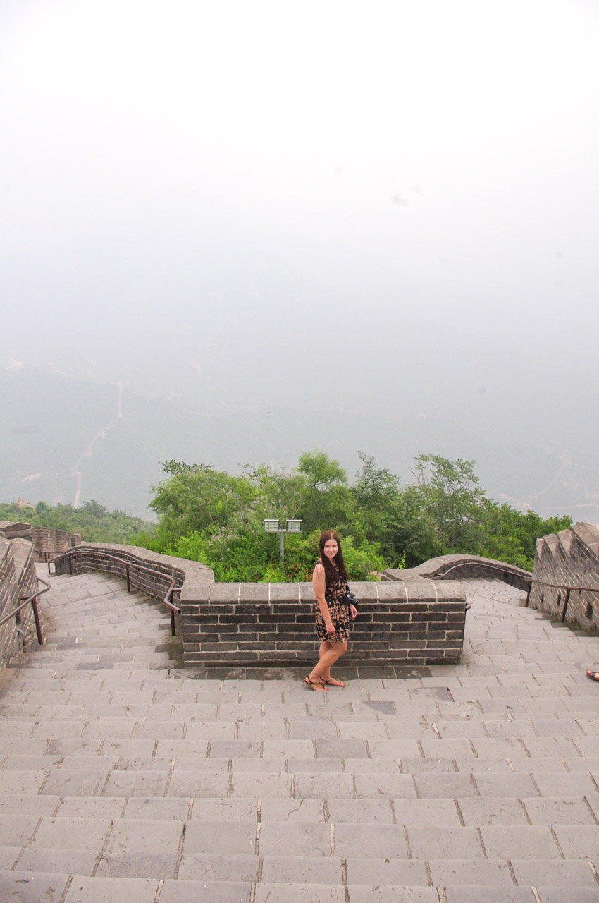 A dark-haired woman in a patterned dress standing on the Great Wall of China