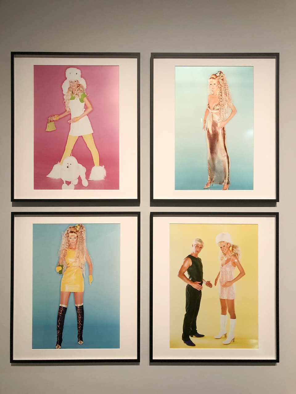 Four framed editorial photos from the '90s portraying a man and a woman against pink, blue, and yellow backgrounds