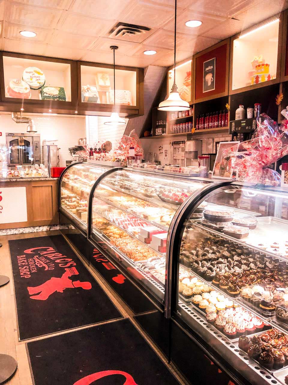 Display cases filled with various cakes and pastries at Carlo's Bake Shop in Hoboken, NJ