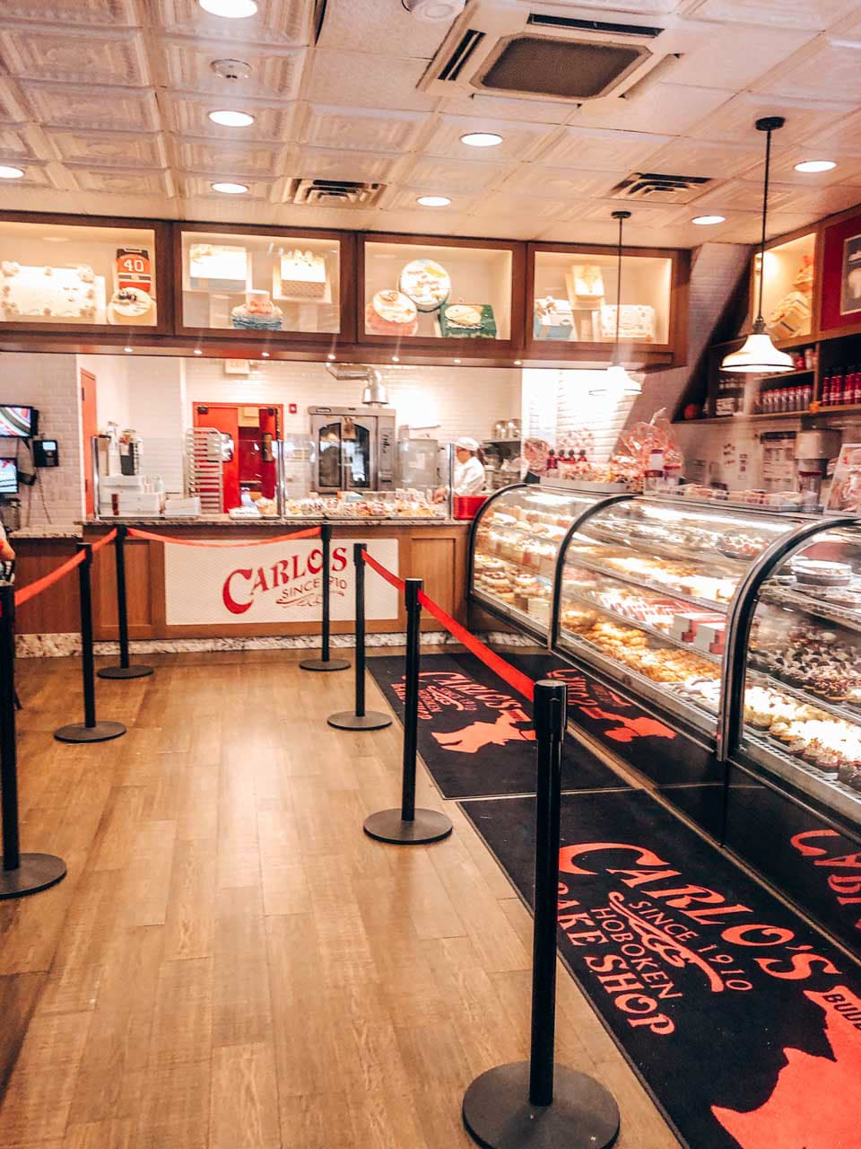 The waiting area, baking area and display cases at Carlo's Bakery in Hoboken, NJ