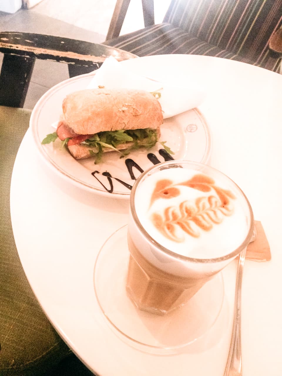 A sandwich and an amaretto latte placed on a table