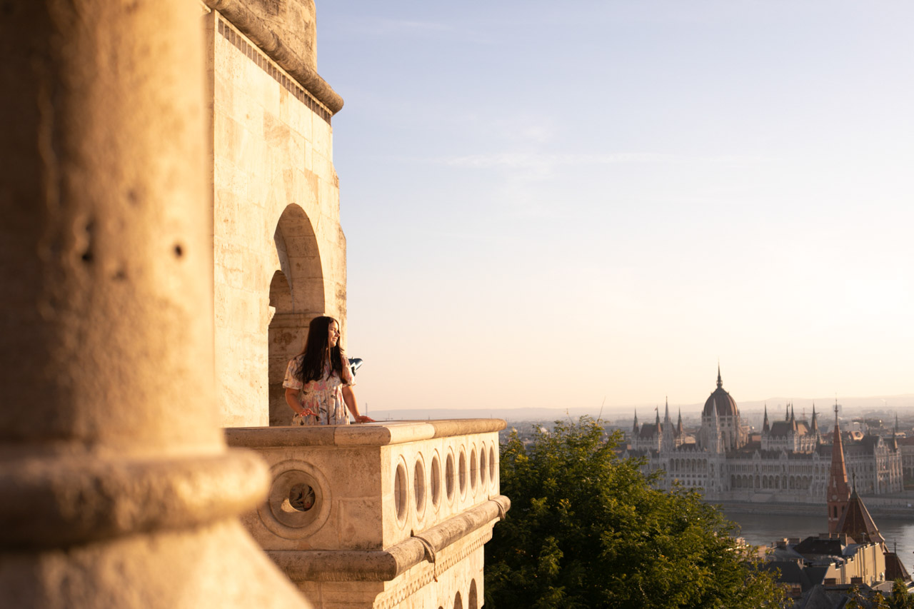 A girl leaning against the ledge of Fisherman's Bastion with the Hungarian Parliament building in the background