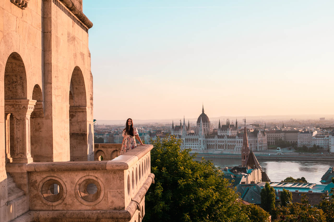 A girl leaning against the ledge of Fisherman's Bastion with the Hungarian Parliament building in the background