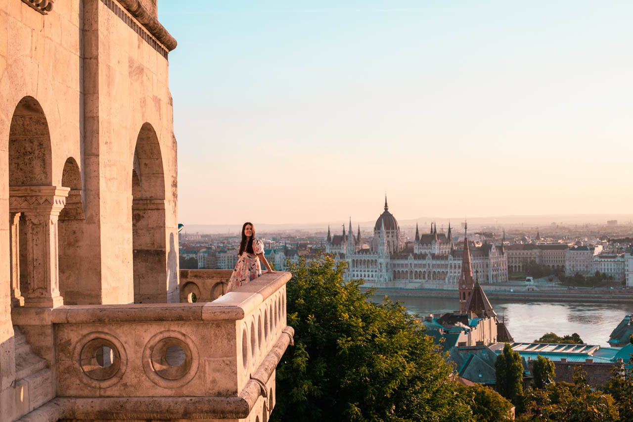 A girl leaning against the ledge of Fisherman's Bastion with the Hungarian Parliament building in the background