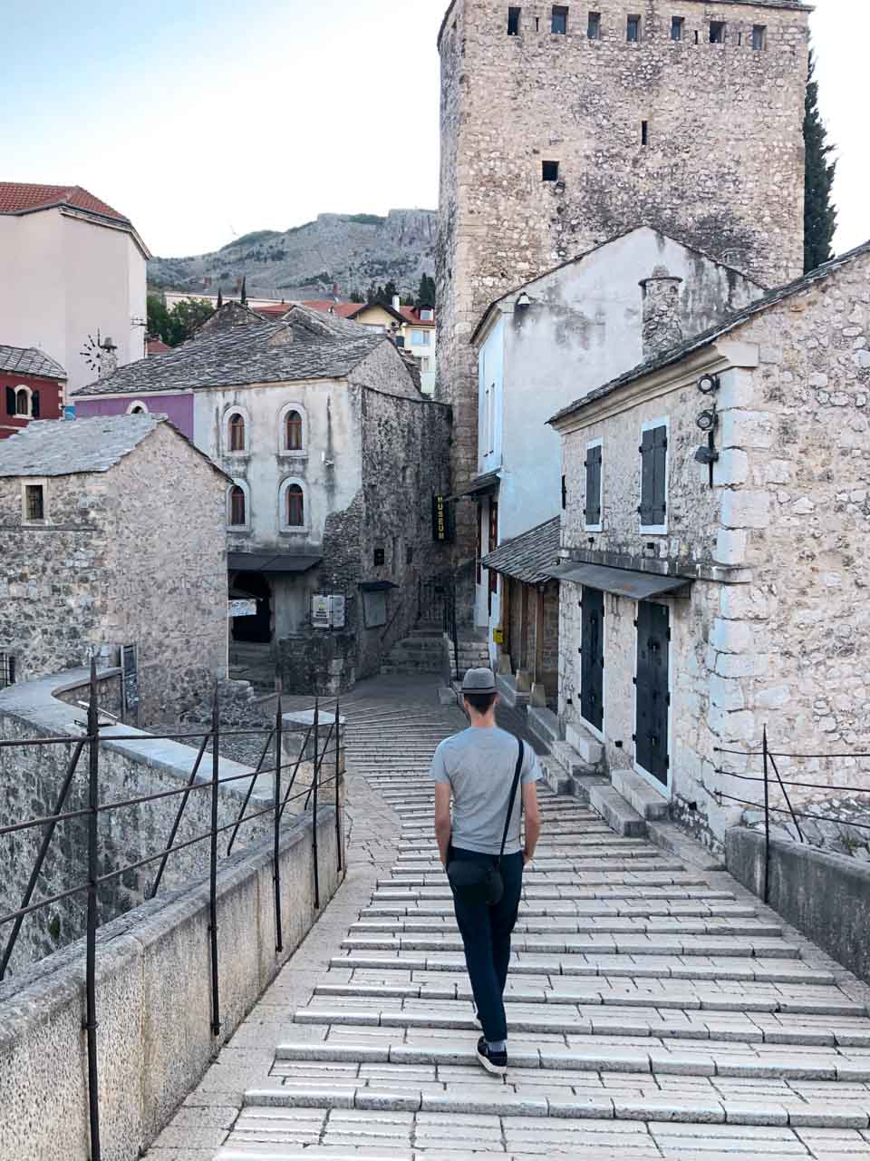 A man walking down the Stari Most (Old Bridge) in Mostar