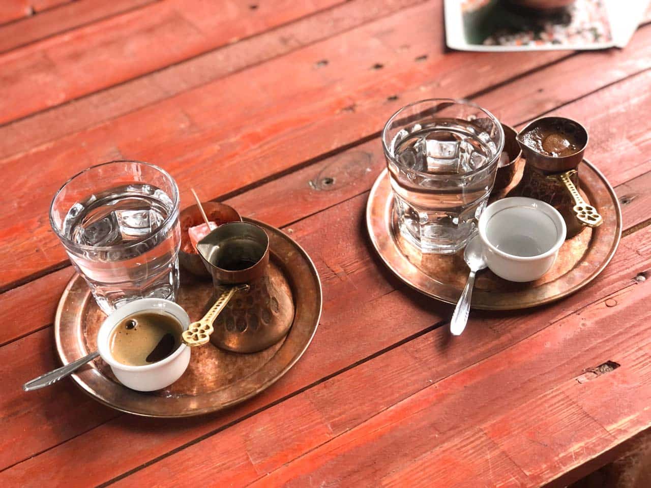 Two trays containing Bosnian coffee and a džezva each on a wooden table