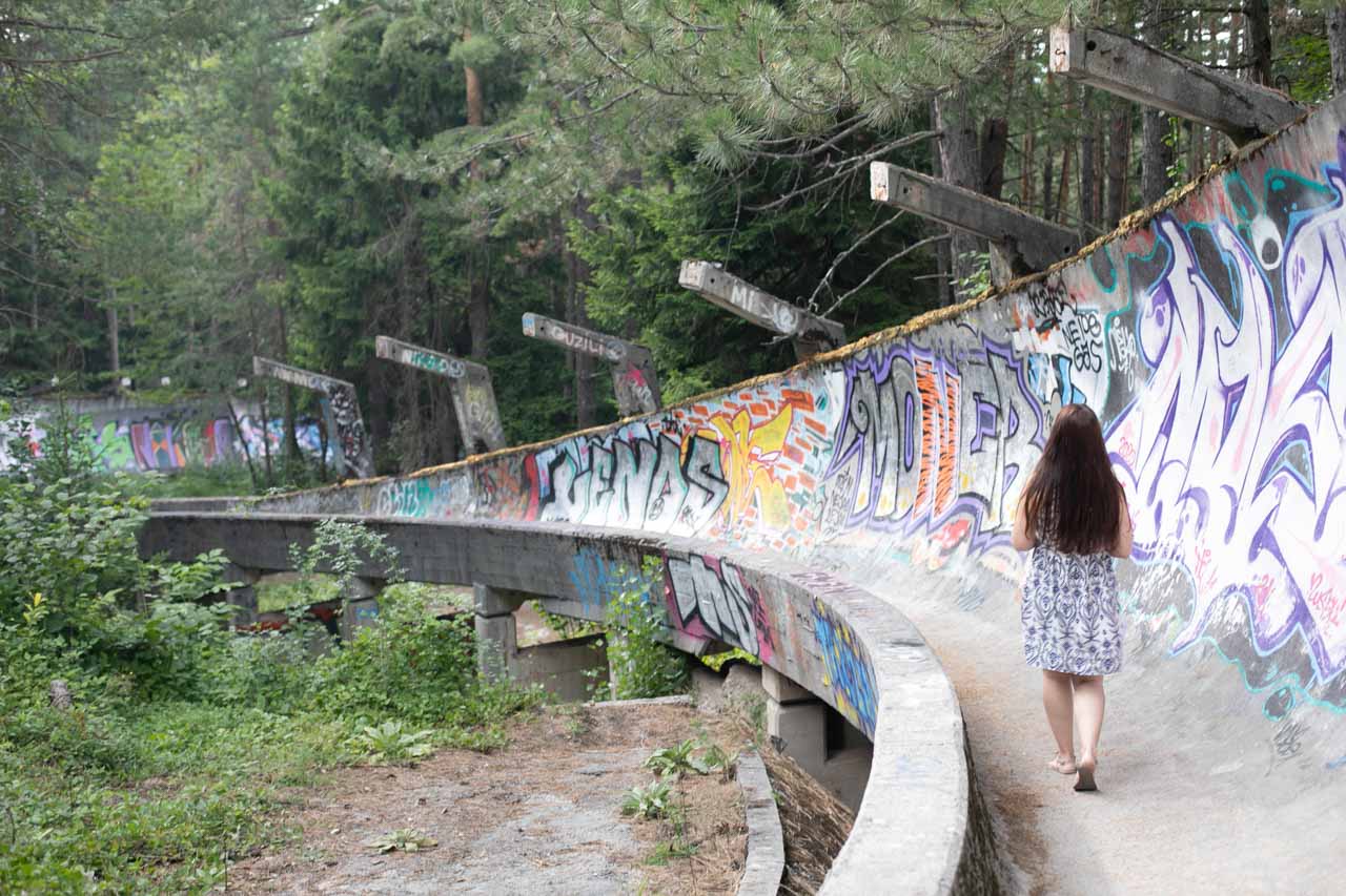 A girl in a summer dress walking on the abandoned Olympic bobsleigh track in Sarajevo