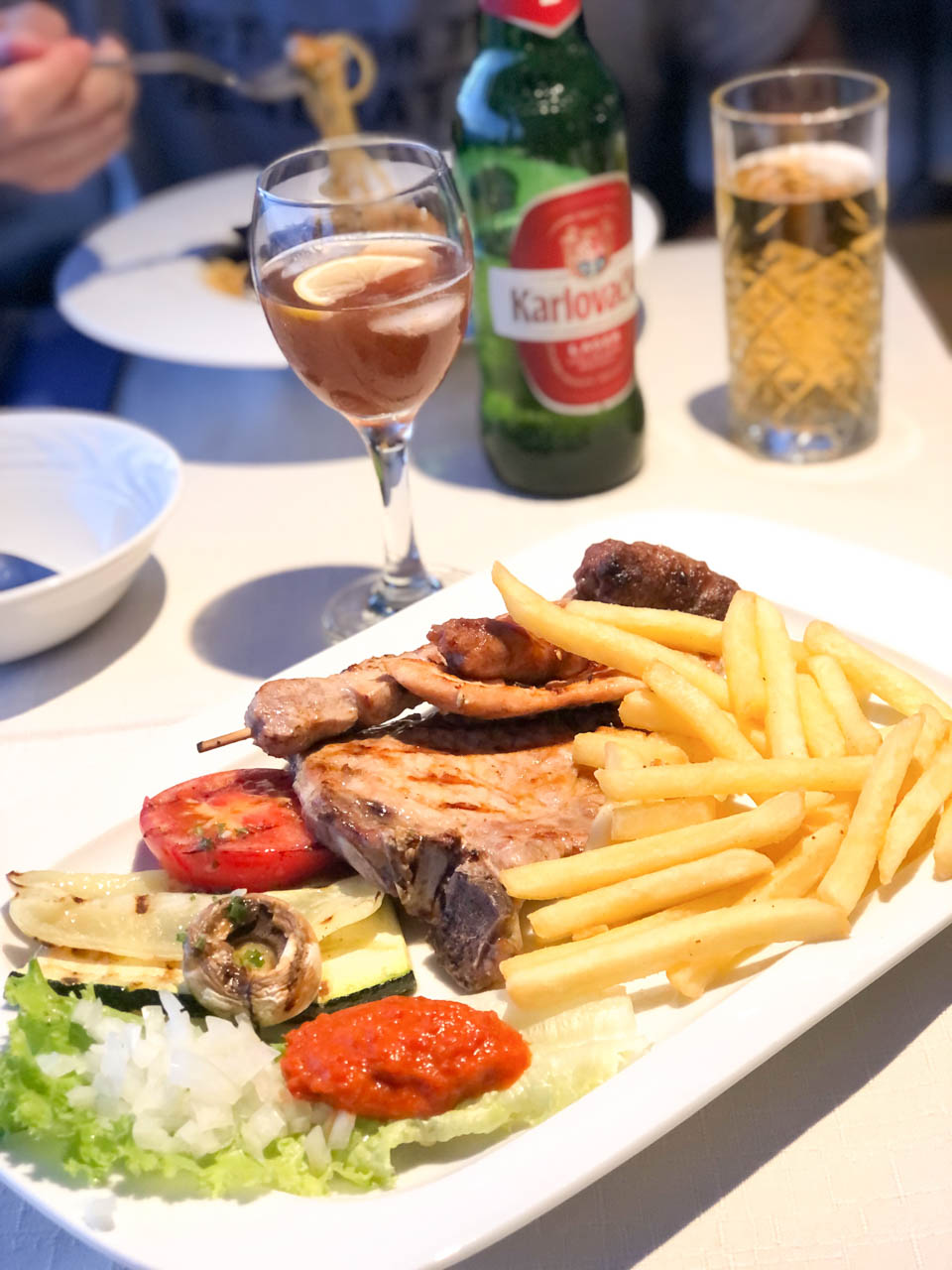 A plate of grilled meat with sides on a table at the Konoba Dinko tavern in Bol, Croatia