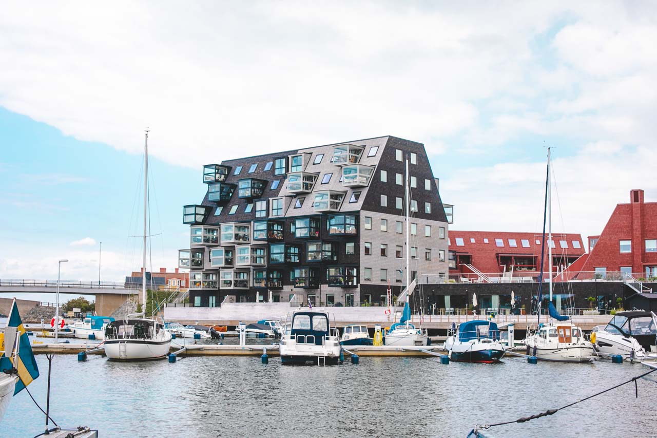 Yachts docked at a port in Karlskrona, Sweden, with a modern apartment building behind them